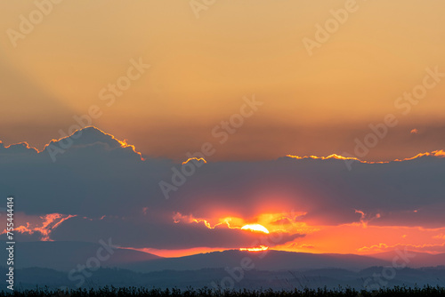 Sunset in the mountains with clouds and sunbeams. Landscape.