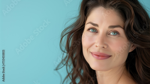 Photoshoot for beauty and wellness magazine featuring a woman in her 30s with prominent lips and cheekbones against a light blue background, portraying youthful appearance.