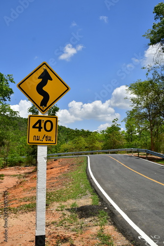 The asphalt road with a speed limit sign at 40 km/h and a curve warning sign in Tub-Lan National Park, Thailand