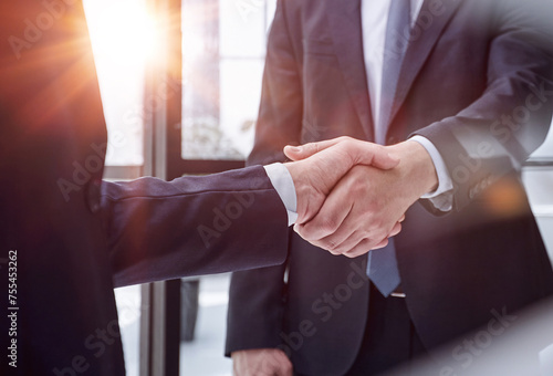 executives shaking hands in front of their manager and a colleague