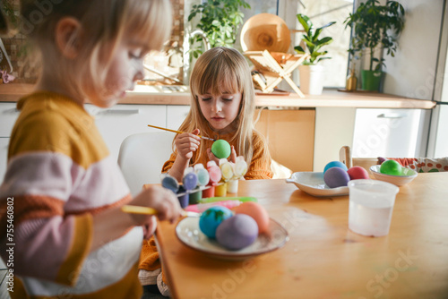 Sisters painting Easter eggs at home photo