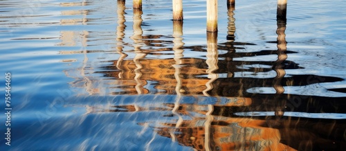 The reflection of a building can be seen in the waters surface, creating a rippled effect. The image captures the mirrored image of the building along with a jetty reflection.