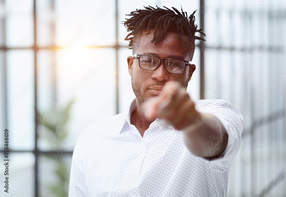 Naklejka premium businessman in glasses pointing at you while standing in a modern office