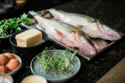 raw fish with cooking ingredients on dark stone background