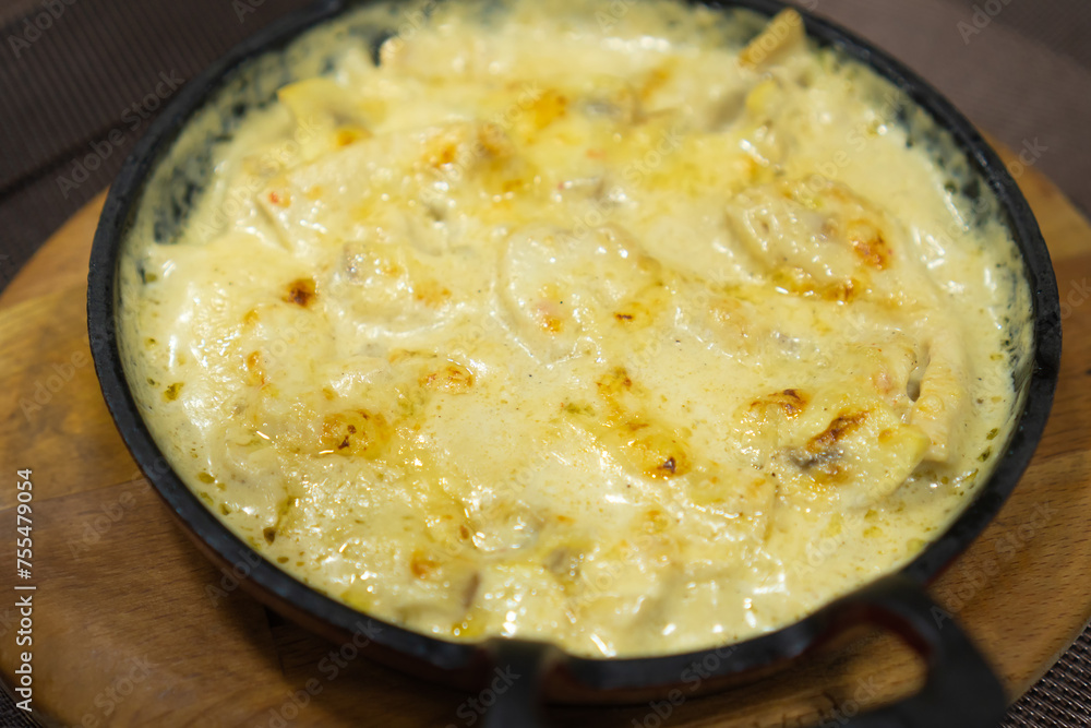 Close-up of mushrooms in sour cream sauce on a cast-iron frying pan for serving dishes in a restaurant Close-up of mushrooms in sour cream sauce on a cast-iron frying pan for serving dishes in a restaurant