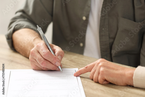 Fotografie Notary pointing to senior man where to sign Last Will and Testament at wooden ta
