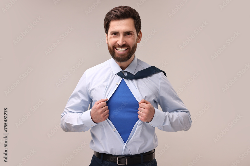 Happy businessman wearing superhero costume under suit on beige background Happy businessman wearing superhero costume under suit on beige background