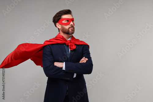 фотографія Confident businessman wearing red superhero cape and mask on beige background