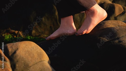 a slow-motion video depicting a teenage girls feet with painted toenails, her dog, balancing on rocks by the tidepool on a pacific coast beach in california photo