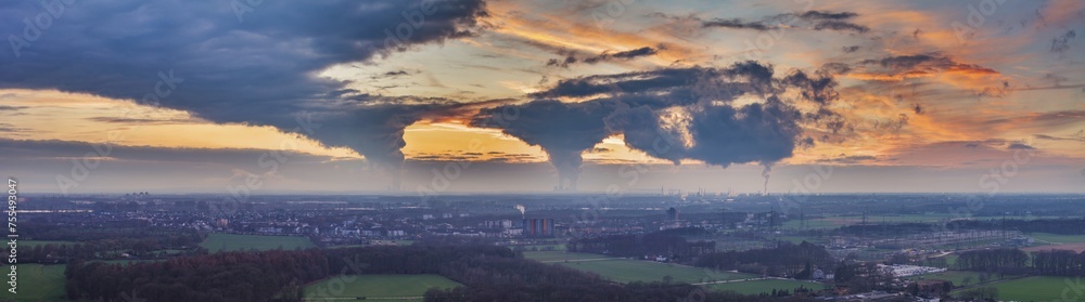 Drone image of the evening sky of the German industrial region of the Ruhr with several chimneys emitting large quantities of exhaust fumes