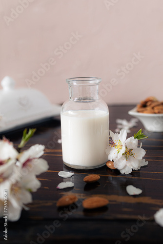 Almond milk with almonds and almond blossoms on the table  the vegan alternative to traditional milk