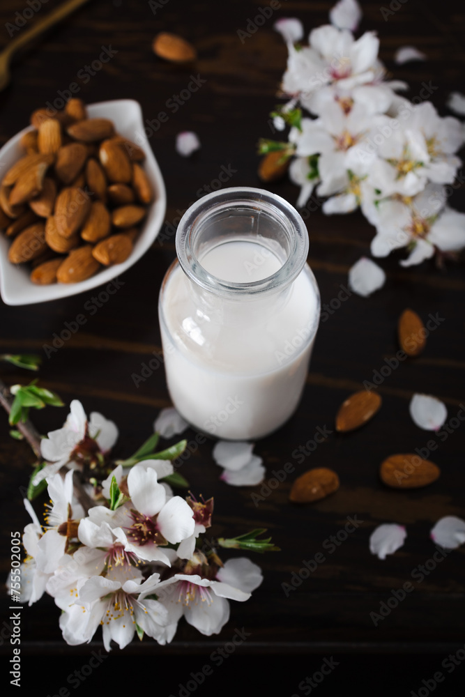 Almond milk with almonds and almond blossoms on the table: the vegan alternative to traditional milk Almond milk with almonds and almond blossoms on the table: the vegan alternative to traditional milk