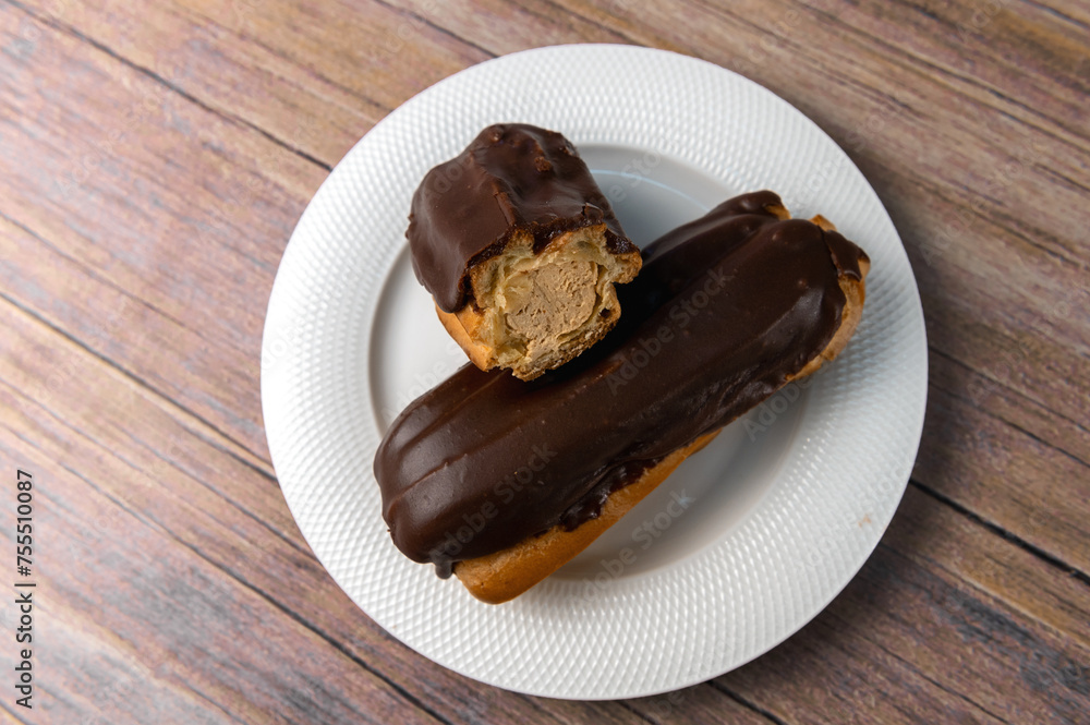 French ecler with chocolate on white plate. Traditional french dessert eclair.