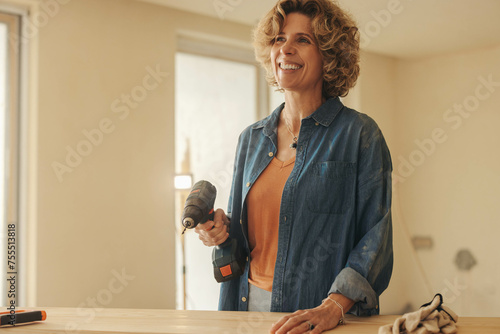 Woman smiling and holding a drill tool during a home kitchen remodeling project © Jacob Lund