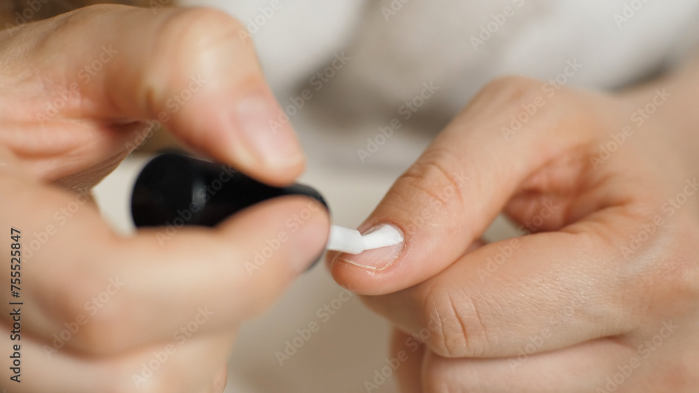 Applying nail polish to the thumb nail. Close-up of a nail brush. Manicure. Beauty care