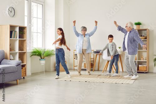 Happy, cheerful family playing and having fun together. Funny grandparents and children having a party at home. Joyful, carefree grandmother, grandfather and kids dancing in a spacious living room
