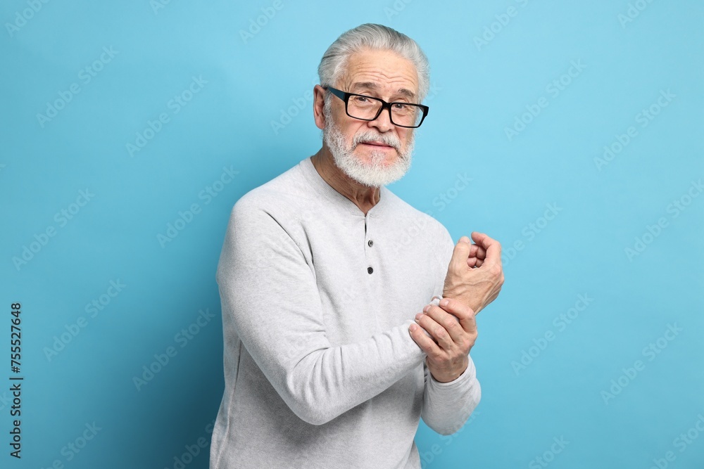 Arthritis symptoms. Man suffering from pain in wrist on light blue background Arthritis symptoms. Man suffering from pain in wrist on light blue background