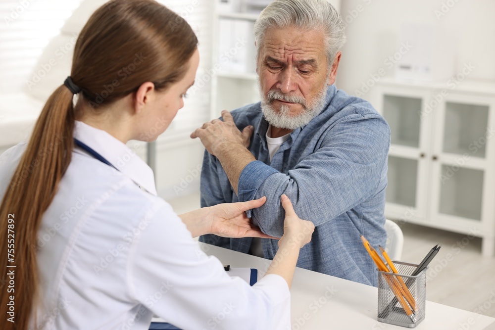 Obraz premium Arthritis symptoms. Doctor examining patient's elbow in hospital