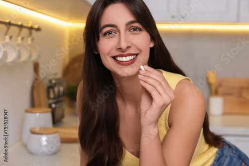 Beautiful woman taking vitamin pill at home