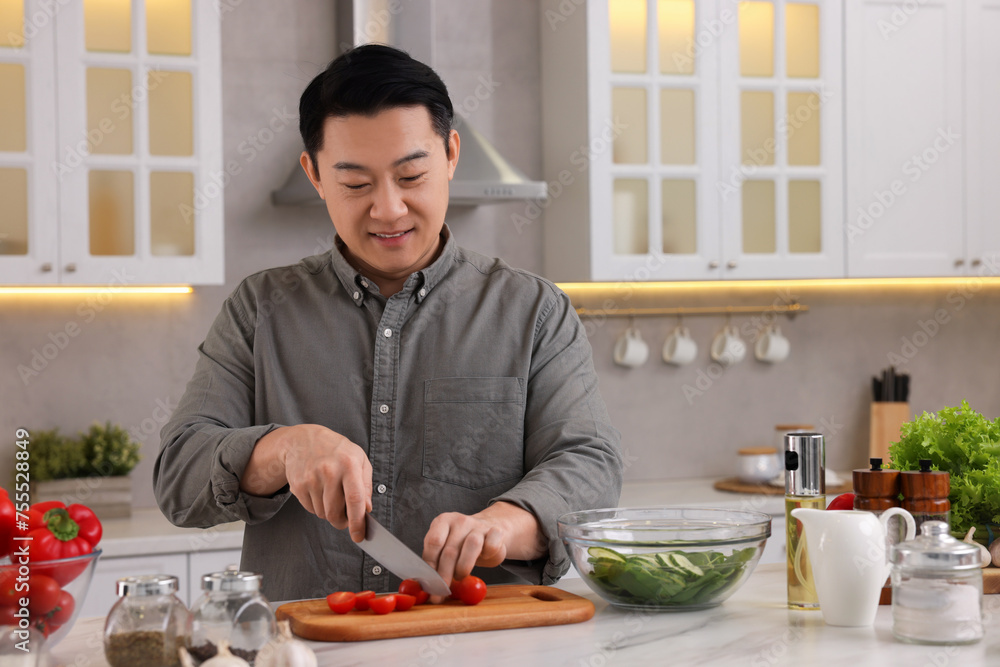 Cooking process. Man cutting fresh tomatoes at countertop in kitchen Cooking process. Man cutting fresh tomatoes at countertop in kitchen