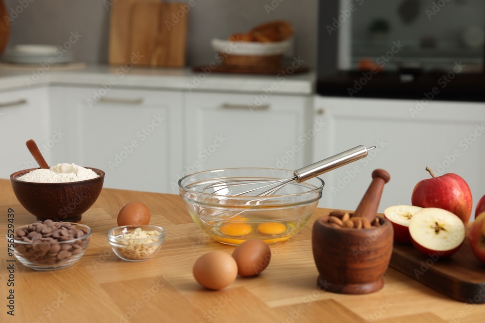 Cooking process. Metal whisk, bowl and products on wooden table in kitchen Cooking process. Metal whisk, bowl and products on wooden table in kitchen