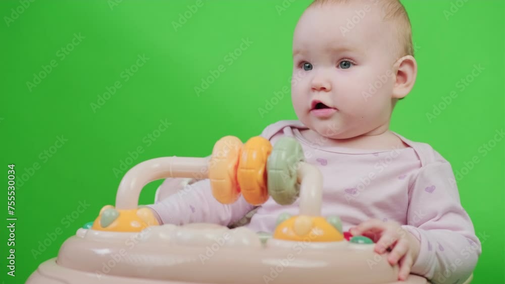 Baby Sitting in High Chair on Green Background. The baby is sitting in a walker Baby Sitting in High Chair on Green Background. The baby is sitting in a walker