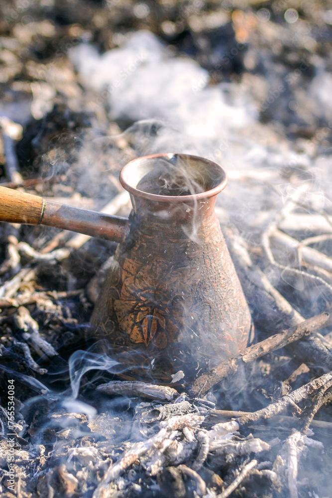 Fototapeta premium Making coffee in cezve on the bonfire when camping or hiking in the nature. Coffee on campfire.