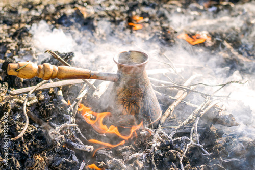 Boiling coffee in turkish cezva on campfire coals. photo