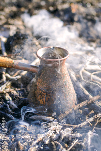 Making coffee in cezve on the bonfire when camping or hiking in the nature. Coffee on campfire.