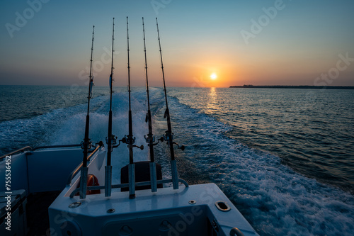 Sunrise behind a fishing boat with fishing rods