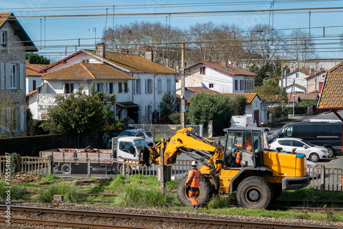 Trabalhadores realizando manutenção nas linhas de comboio com máquina de carregamento frontal em meio a uma área urbana photo