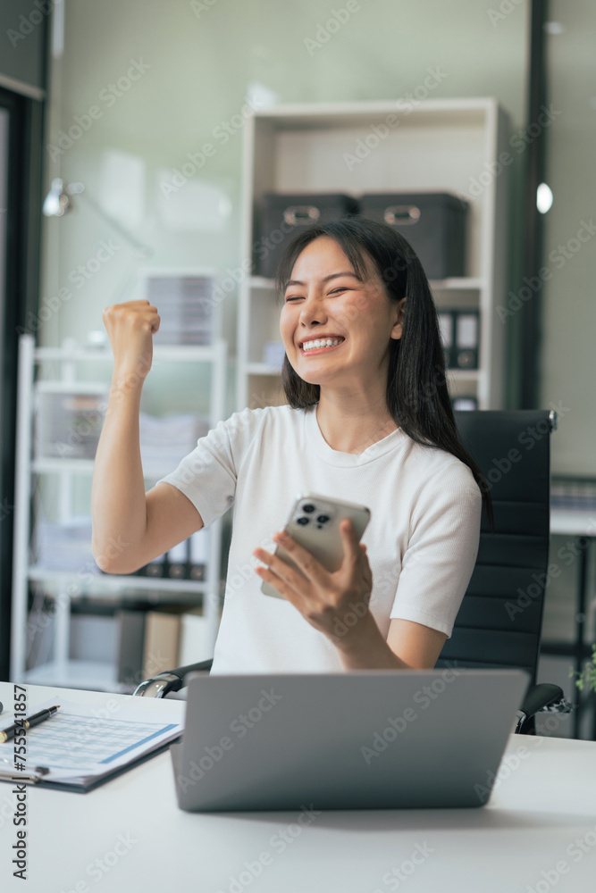Happy Asian woman holding a smartphone, happy smiling, getting bonus money.