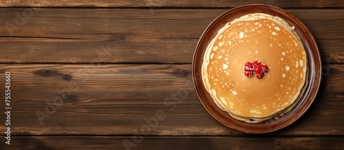 A top view of a golden-brown pancake on a rustic wooden table, with a dollop of butter melting on top and a drizzle of maple syrup. The plate is slightly angled, showcasing the fluffy texture of the photo