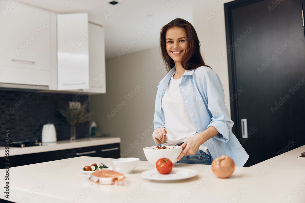 Woman preparing healthy salad in the kitchen with fresh vegetables on the counter Woman preparing healthy salad in the kitchen with fresh vegetables on the counter
