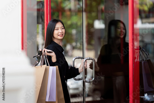 Cheerful Beautiful Asian woman holding shopping bags in shopping in the city on holiday Black Friday