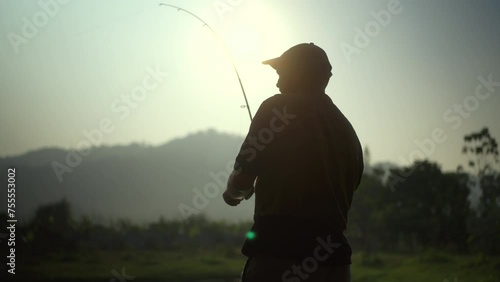 Excited emotion of Handsome fisherman fishing as a leisure activity during his vacation at the lake on sunset. Relax and hobby concept.