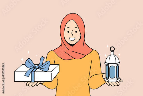 Muslim woman invites to celebrate ramadan, holy islamic holiday, holding gift box and lantern. Girl observes muslim traditions and customs gives gifts to loved ones during month of ramadan