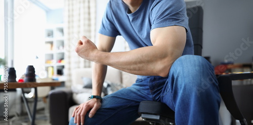 Man bending his arm and straining his biceps closeup. Home sports training concept