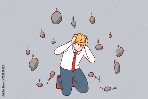 Man saves himself from falling rocks during earthquake by using hardhat to protect head at work. Confident manager is not afraid of earthquake, knowing safety rules in event of emergency situations