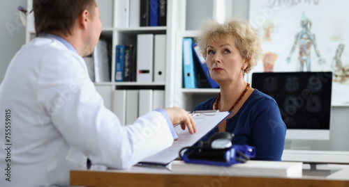 Doctor interviewing elderly woman patient in clinic office. Taking medical anamnesis concept