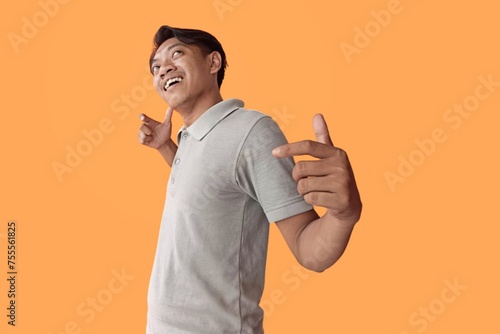 Asian man standing over orange background celebrating crazy and amazed for success with arms raised and open eyes screaming excited. winner concept