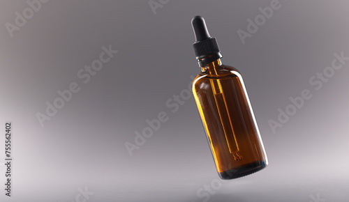 Glass bottle with cosmetic oil on gray background closeup. Cosmetology sale of cosmetic products concept