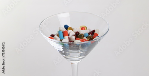Glass with lot of multicolored medical capsules on white background closeup. Polypharmacy concept