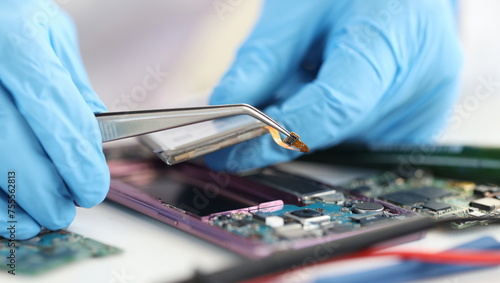 Master repairman inserting microchip into mobile phones closeup. Mobile phone repair and maintenance concept