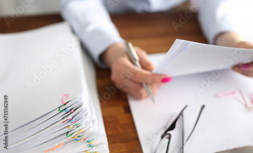 Woman secretary working with papers at her desk closeup. Paperwork concept