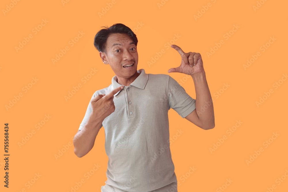 Handsome Asian man standing over orange background pointing fingers to camera with happy and funny face. good energy and vibes. Handsome Asian man standing over orange background pointing fingers to camera with happy and funny face. good energy and vibes.