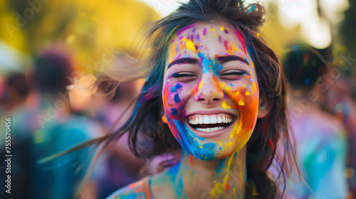 Happy laughing woman with colorful holi paint on her face