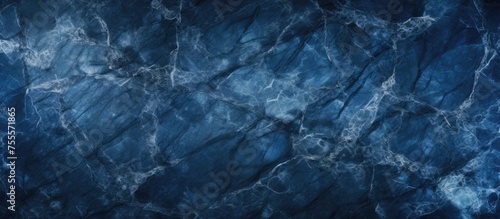 A close-up view of a dark blue marble texture background, showcasing intricate cracks and patterns. The deep blue hues create a mysterious and elegant atmosphere, perfect for adding a touch of