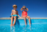 Siblings enjoying sunny day together dip their feet in pool