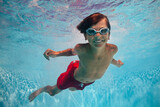Underwater shot of a cheerful boy smiling in camera while swim